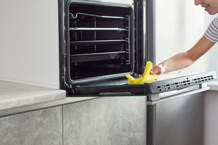 mano con panno giallo che pulisce forno