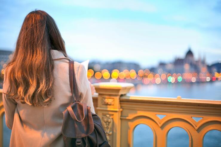 Donna di spalle che osserva il panorama da un ponte su lungofiume
