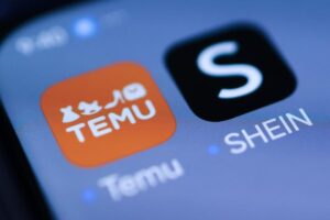 Sfondo smartphone con app Temu e Shein in primo piano