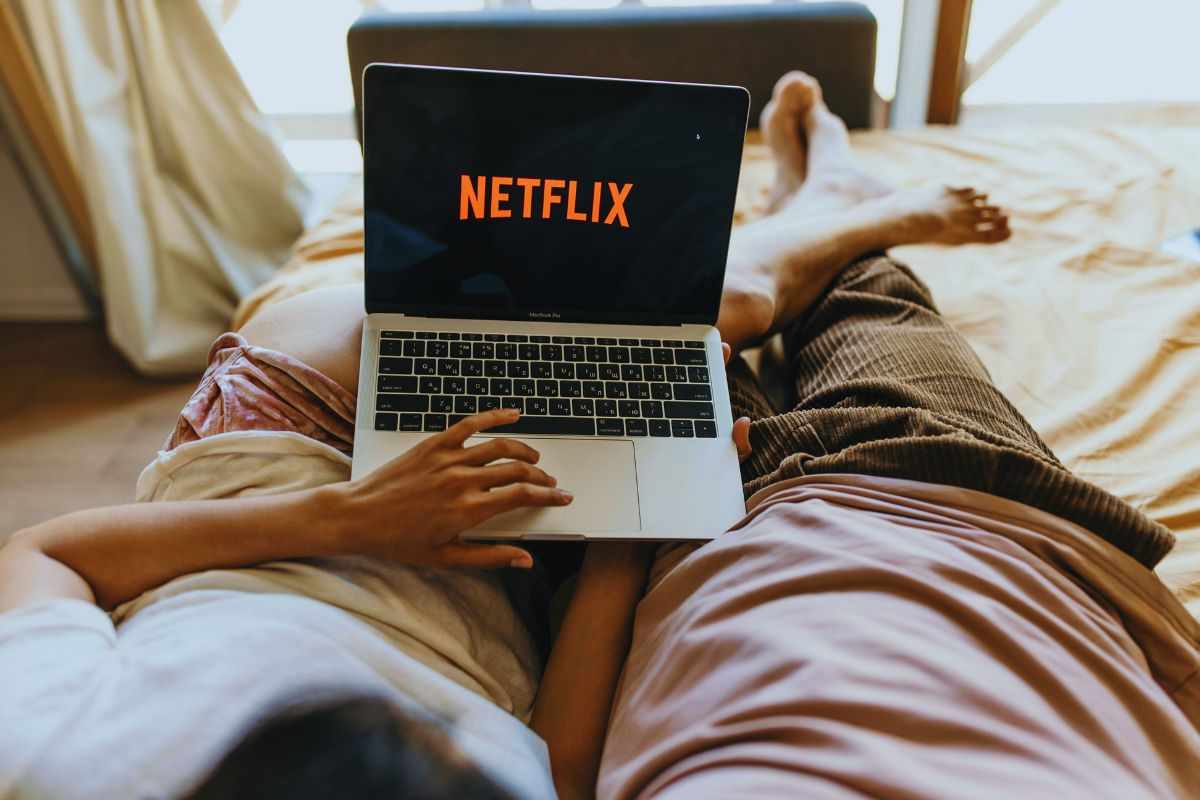 Coppia che guarda Netflix dal letto tramite un laptop