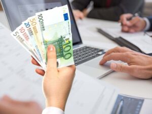 sfondo persone alla scrivania trattano documento e mano con banconote euro