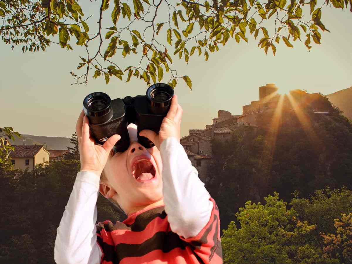 sfondo borgo italiano e bambino che guarda con binocolo