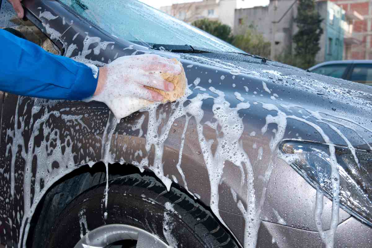 uomo lava la propria auto già insaponata