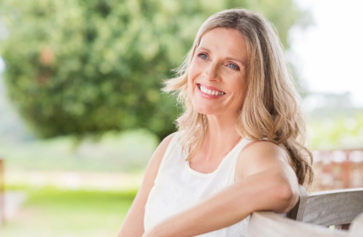 donna che sorride seduta su una panchina al parco