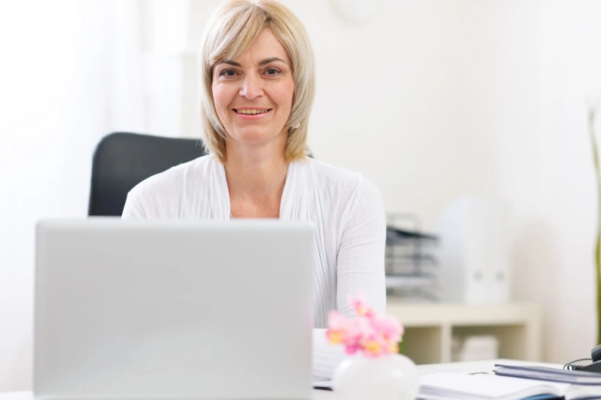 donna sorridente in ufficio seduta di fronte al computer