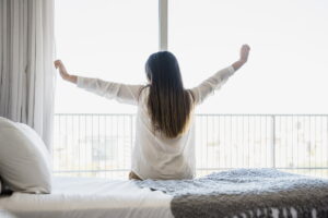 Donna che si alza al mattino rivolta verso le finestre